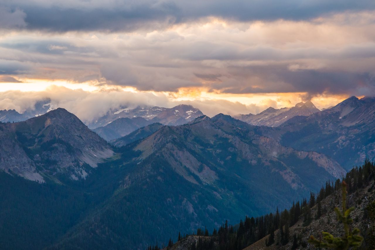 A stunning view of mountain ranges under a dramatic sky during sunset, showcasing nature's beauty.