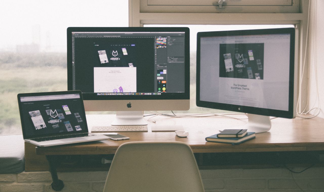 our-story Stylish and efficient workspace with multiple monitors, laptop, and smartphone, showcasing a web design project.