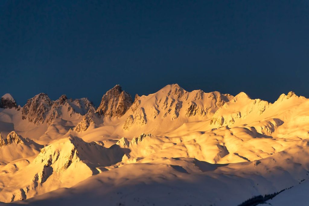 A stunning view of sunlit snowy mountain peaks at sunset, showcasing nature's beauty.