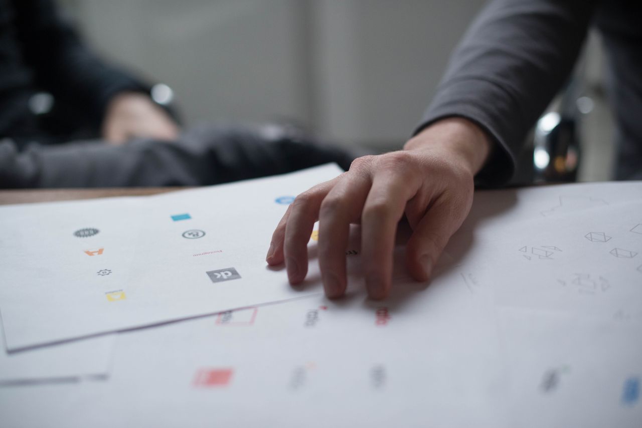 services-bg A close-up shot of a hand reviewing various logo designs on paper, ideal for business concepts.